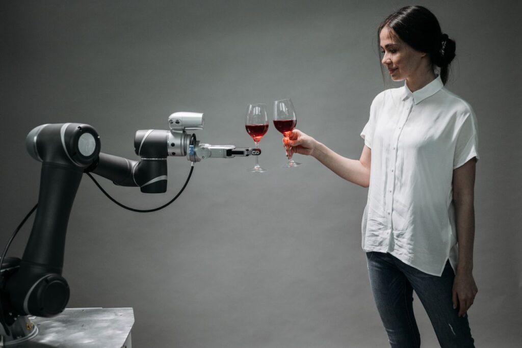 pexels-photo-8439089-8439089 A woman in casual attire shares a toast with an advanced robotic arm, reflecting modern technology and innovation in robotics.